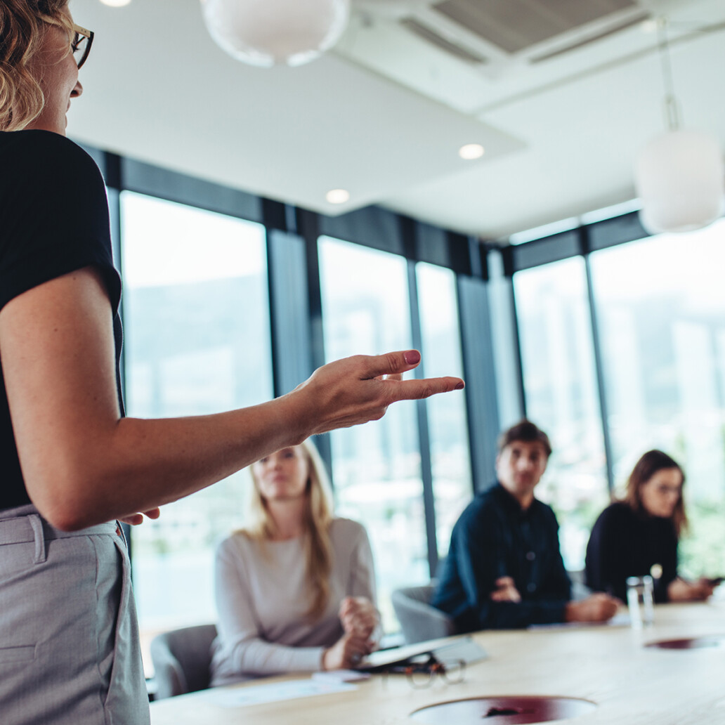 Businesswoman making a presentation to her colleagues in office. Office colleagues sitting at the conference room while listening to a presentation.