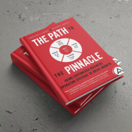 Three hardcover copies of the Path to the Pinnacle from Gregory Cleary and Michael Erath on a stone background