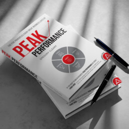 Copies of Peak Performance by Gregory Cleary laid on each other, with pens next to them