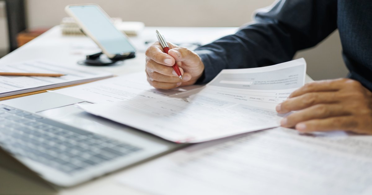 Reviewing a franchise disclosure document with reading glasses and a calculator